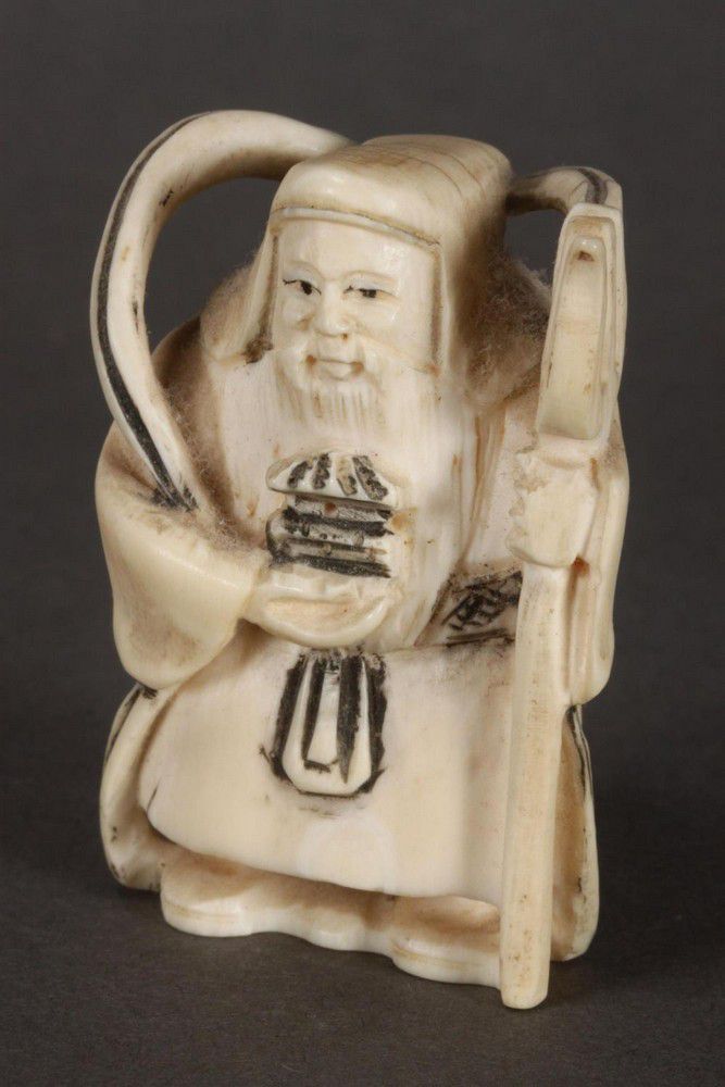 Japanese carved ivory netsuke, depicting a figure holding a… - Netsuke