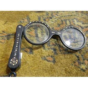 A pair of lognette glasses with rhinestone highlights. A…