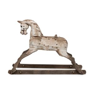 An antique rocking horse, carved wood with remains of white…