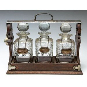 An antique oak tantalus with a matching set of three cut…