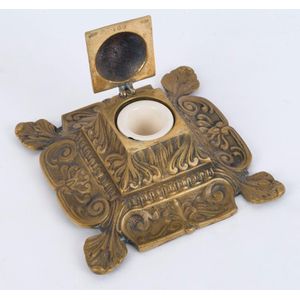 An antique English cast brass ink well with ceramic ink pot,…