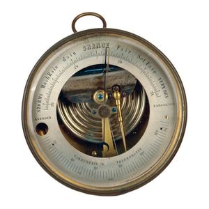 An old circular brass cased aneroid barometer with ring…