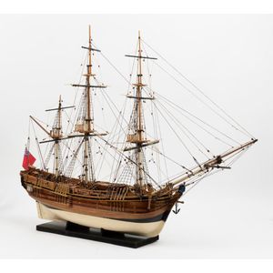 An intricate scale model of a three masted ship, with a sailor…