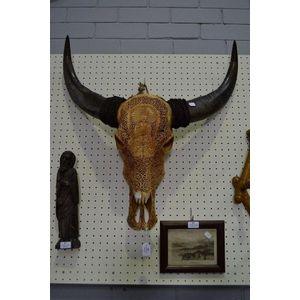 An intricately carved buffalo skull featuring Hindi Buddha…