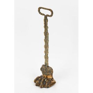 An antique cast brass doorstop in the form of a clawed foot,…