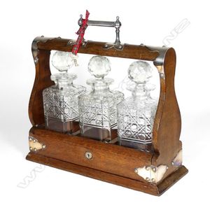 An Edwardian oak and silver plate tantalus, three decanters,…