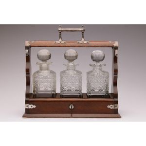 An Edwardian oak tantalus with silver plated Walker and Hall…