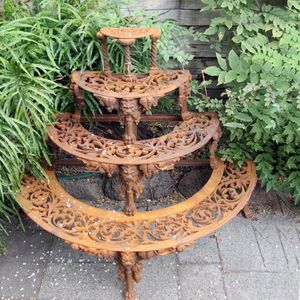 A stepped cast iron plant stand with four tiers, each with…