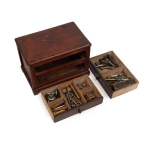 A collection of antique watch makers tools in an antique cedar…