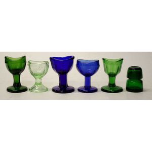 Five coloured glass eye baths 6-7 cm high and a small medicine…