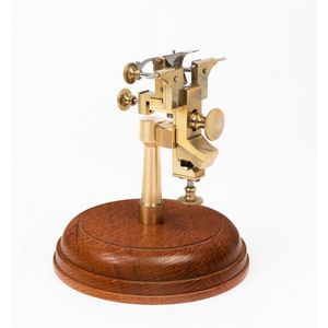 A watchmaker's truing tool, circa 1880, mounted on wooden base,…