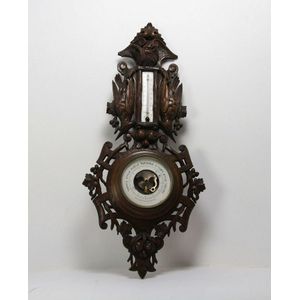 An ornately carved beech wood wall barometer decorated with…