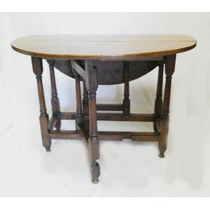 A Georgian oak gate leg table, the plain circular four plank…