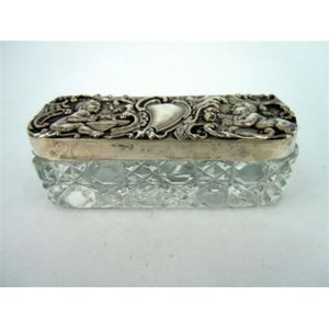 An Edwardian silver lidded cut glass trinket box, cherub form…