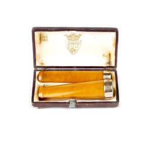 An amber and gold cigar holder, together with a matching…