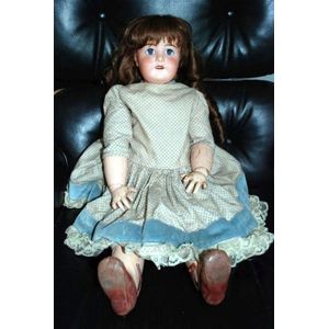 A porcelain headed doll, glass eyes, six teeth, with jointed…