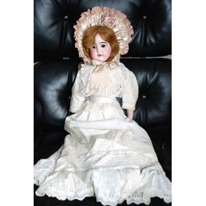 A porcelain headed doll, glass eyes, four teeth upper, with…