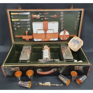 A leather bound picnic case, partly fitted with contents. The…