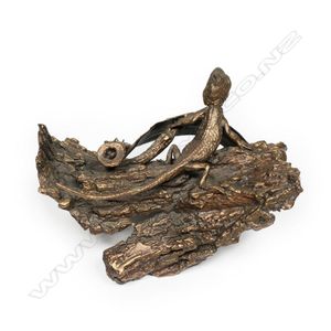 A small bronze sculpture of an Australian lizard, on bark…
