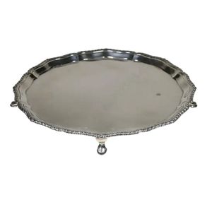 A silver salver, pie crust rim, plain interior, raised on four…