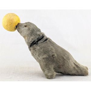 A vintage clockwork grey plush fur seal, balancing a yellow…