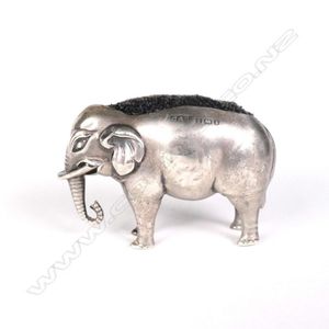 An Edwardian silver elephant pin cushion, a dark velvet pad…