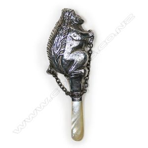A silver and mother of pearl baby rattle, the top in the form…
