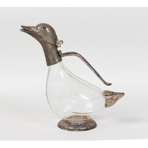 A glass and silvered metal wine decanter in the form of a duck,…