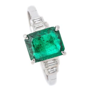 A platinum emerald and diamond ring, centring an emerald cut…