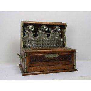 An ornately carved Edwardian oak three bottle tantalus. 33 cm…