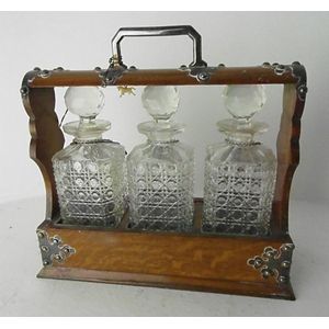 An Edwardian oak tantalus, comprising three cut crystal…