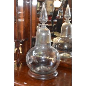 A large glass apothecary bottle with stopper on a wooden base…