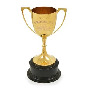 A gold 1946 Hauraki cup on ebonised stand, the shallow tapering…