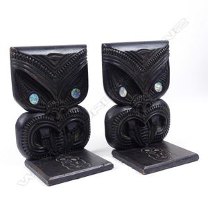 A pair of Maori folk art bookends, dark stained wood, carved as…