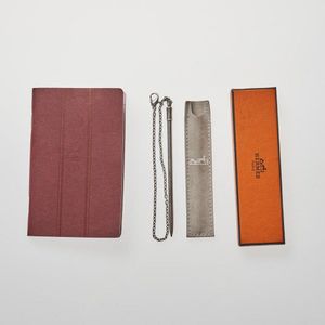 A Hermes burgundy address notebook and a Hermes silver pencil…
