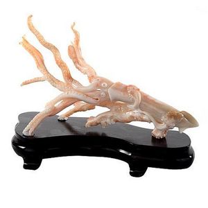 A Chinese carved coral squid on fitted stand. Length 25 cm.