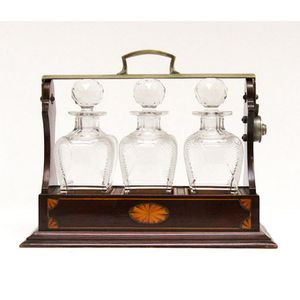 A Sheraton Revival mahogany three bottle glass tantalus stand
