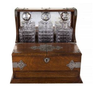 Edwardian oak three bottle tantalus. Containing three spirit…