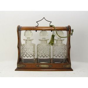 An oak three bottle tantalus. 27 cm high, 35 cm wide, 13 cm…