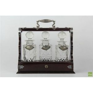 Mahogany tantalus with three silver labelled decanters with…