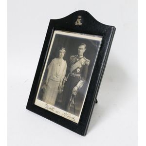 A vintage leather photo frame holding a signed photograph of…