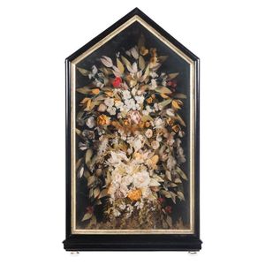 An unusual bird feather floral arrangement in a glazed display…