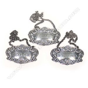 Three silver decanter tickets, embossed with shells, husks and…