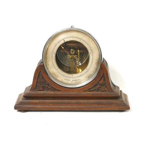 A vintage aneroid barometer, circular plated case, supported on…