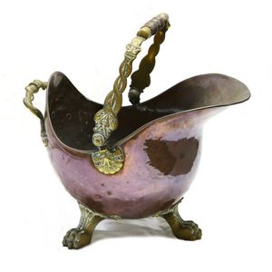 An ornate copper coal scuttle, helmet form, raised on three paw…
