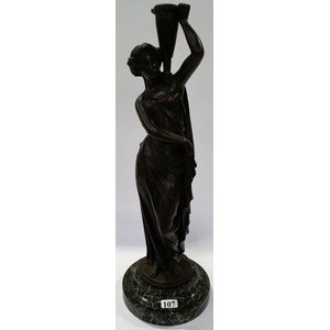 A bronze classical figural candle holder, signed Jean Bulio,…