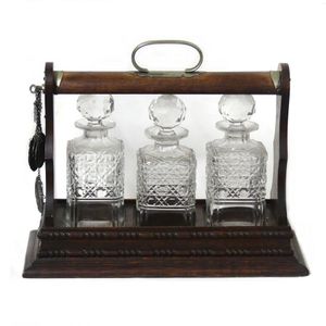 An Edwardian oak three bottle tantalus, with the original…
