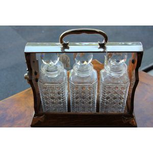 A Victorian oak cased three bottle tantalus by Geese Banjamin,…