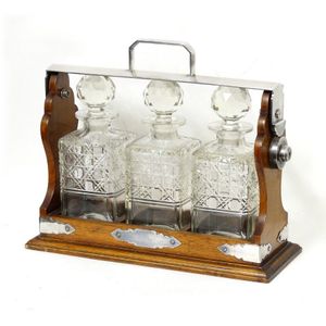 An Edwardian oak and silver plated framed three bottle tantalus,…