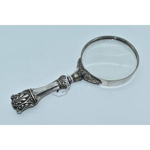 An ornately embossed sterling silver magnifying glass,…